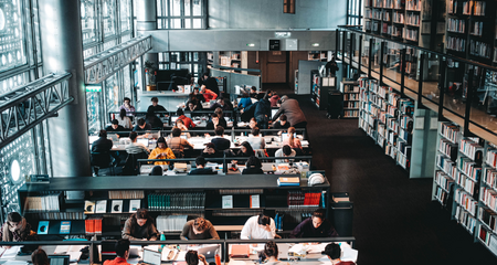 Studierende arbeiten und lernen gemeinsam in einer modernen, hellen Universitätsbibliothek
