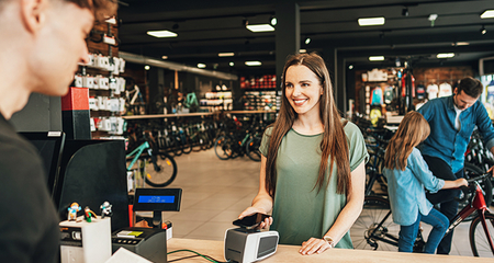 Eine Frau zahlt in einem Fahrradgeschäft an einem POS-Terminal mit Karte