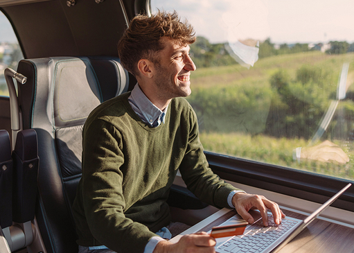 Mann sitzt in der Bahn und bezahlt seinen Einkauf von unterwegs