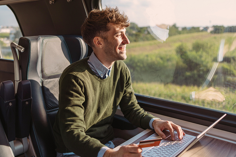 Mann sitzt in der Bahn und bezahlt seinen Einkauf von unterwegs