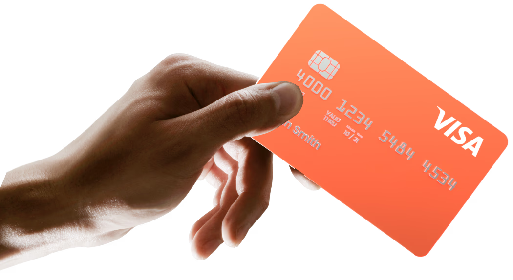 Nahaufnahme einer Hand, die eine orangefarbene Visa-Kreditkarte zwischen Daumen und Zeigefinger hält.
