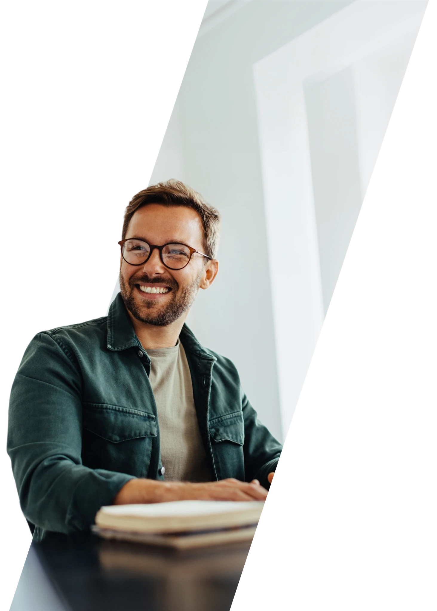 Lächelnder Mann mit Brille sitzt an einem Tisch in einem modernen Büro.