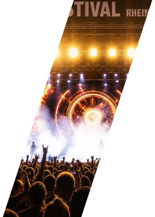 Besucher feiern vor einer beleuchteten Konzertbühne auf einem Musikfestival.